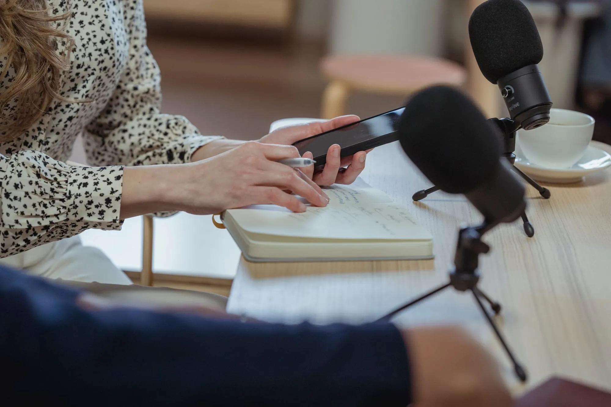 Entrevista com microfones e celular gravando sobre a mesa