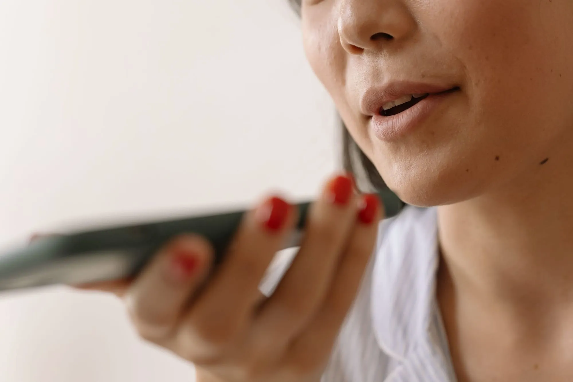 Mulher grava uma mensagem de voz, com o celular perto da boca